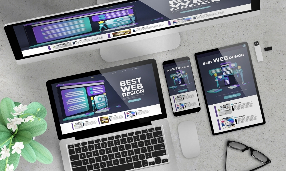 Top-down view of desktop monitor, laptop, tablet, and smartphone displaying a 'Best Web Design' page, illustrating custom built websites across devices.